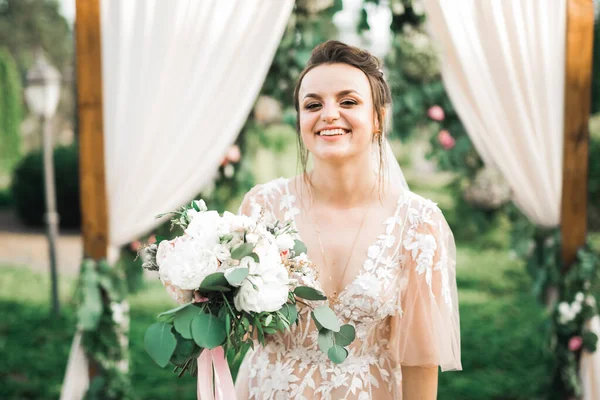 Gelin çiçekli büyük ve güzel bir düğün buketi tutuyor.