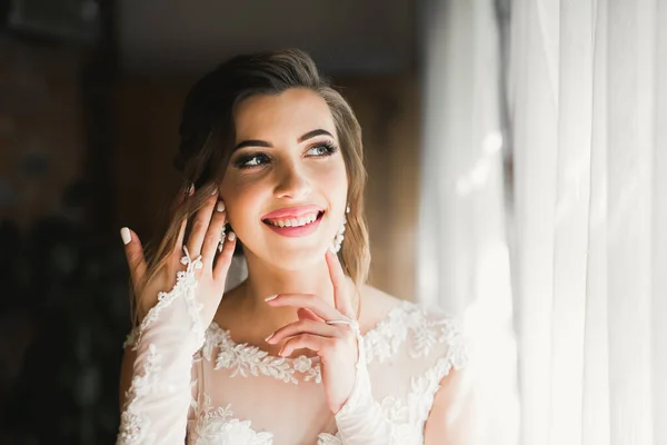 Preciosa novia en bata posando y preparándose para la ceremonia de boda cara en una habitación — Foto de Stock