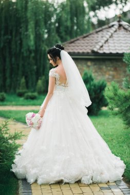 Gelin çiçekli büyük ve güzel bir düğün buketi tutuyor.