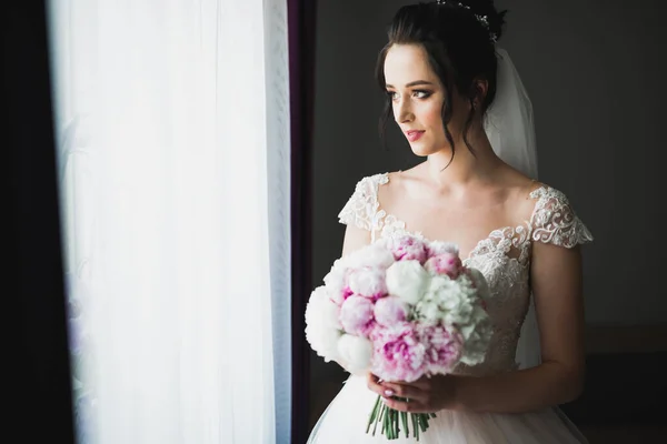 Hermosa novia con vestido de novia de moda con plumas con maquillaje de lujo deleite y peinado, estudio sesión de fotos interior —  Fotos de Stock