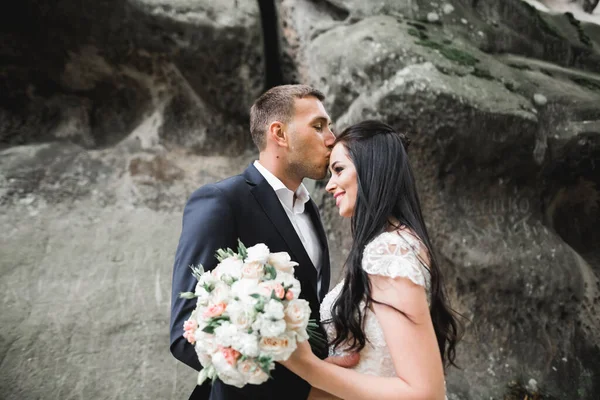 Hermosa joven pareja de boda posando con ramo de flores en las manos —  Fotos de Stock