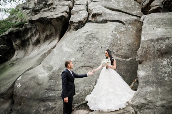 Belle mariée magnifique posant pour se toiletter et s'amuser près des montagnes avec une vue imprenable, espace pour le texte, couple de mariage — Photo