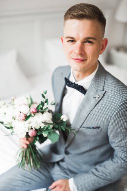 Yaka çiçeğiyle poz veren mutlu yakışıklı damat.