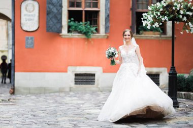 Gelin çiçekli büyük ve güzel bir düğün buketi tutuyor.