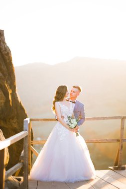 Doğadaki düğün çifti birbirine sarılıyor. Beyaz elbiseli güzel bir kız. Takım elbiseli adam