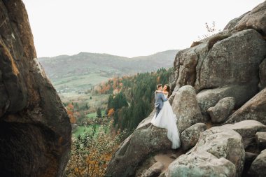 Harika bir gelin damada poz veriyor ve harika manzaralı dağlarda eğleniyor. Mesajlaşacak yer, düğün çifti.