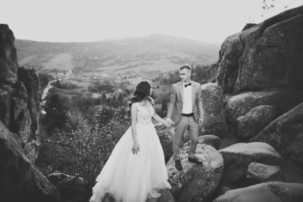 Hermosa novia hermosa posando para el novio y divertirse cerca de las montañas con una vista increíble, espacio para el texto, pareja de boda — Foto de Stock