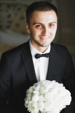Güzel adam, damat elinde çiçeklerle büyük ve güzel bir düğün buketi tutuyor