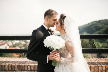 Güzel, genç bir çift ellerinde çiçeklerle poz veriyorlar.