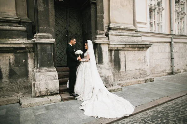 Preciosa pareja feliz boda, novia con vestido blanco largo posando en la hermosa ciudad —  Fotos de Stock