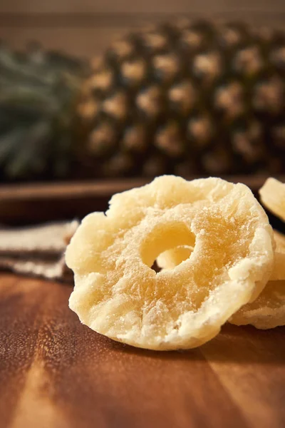 Dried and candied pineapple rings on wooden background
