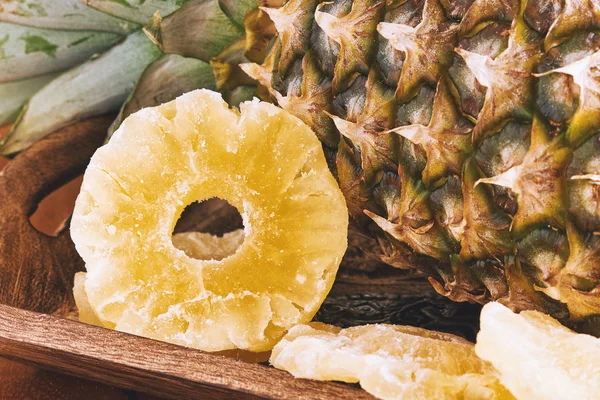 Dried and candied pineapple rings in wooden plate
