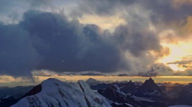 Bulutlar ve Günbatımı Bu stok video zaman atlamalı bir çekim kalın bulutlar ve güzel bir gün batımı karla kaplı dağlar üzerinde.