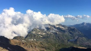 Bulutlu Dağlar Zaman Akımı Mavi gökyüzünde büyük beyaz bulutlar bir zaman atlamasında dağların üzerinden yuvarlanıyor.