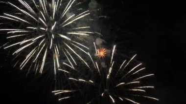 This stock footage features a close-up shot of colorful fireworks exploding in the air at night. As they explode, these fireworks splash shiny sparks across the dark background, forming some amazing patterns. 
