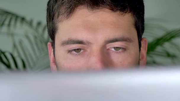 男サーフィンインターネットは 自宅で彼のコンピュータ上でインターネットをチェック灰色の目を持つ男の優れた映像を示すビデオです この3840X2160ビデオクリップは インターネットや技術と関係のあるビデオプロジェクトで素晴らしい見えます — ストック動画