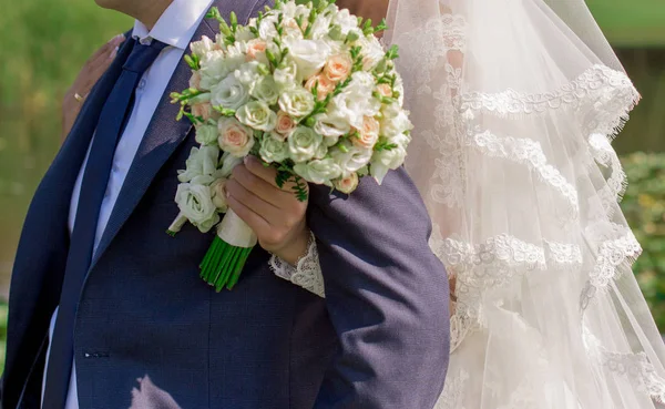 Braut mit Strauß in der Hand umarmt Bräutigam — Stockfoto