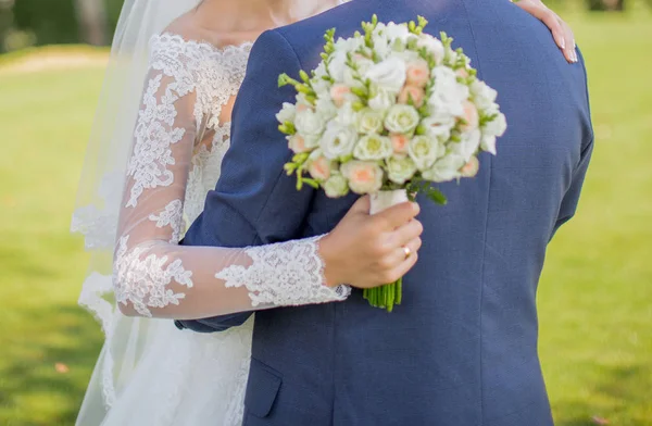 Sposa con bouquet in mano abbracciando lo sposo — Foto Stock