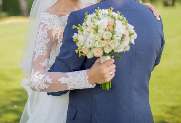 Braut mit Strauß in der Hand umarmt Bräutigam — Stockfoto