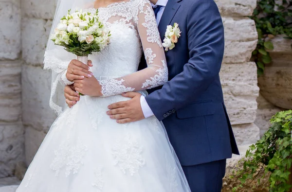 Жених обнимает невесту свадебным букетом — стоковое фото