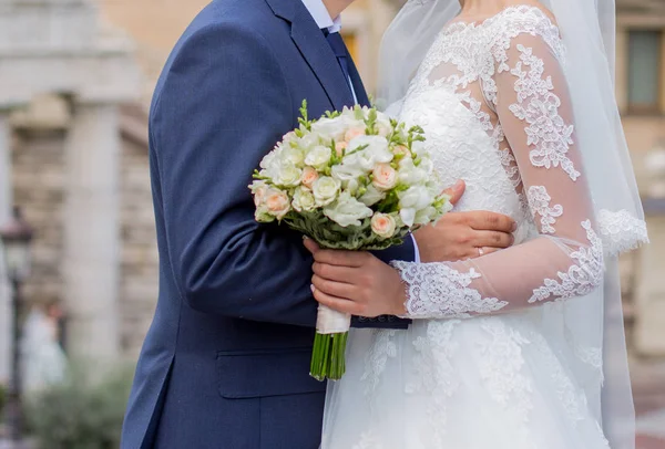 Der Bräutigam umarmt die Braut mit einem Brautstrauß — Stockfoto