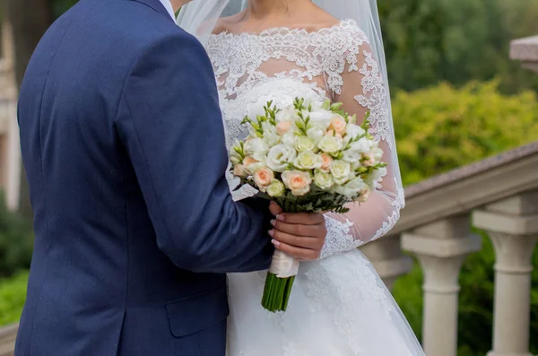 Le marié embrasse la mariée avec un bouquet nuptial — Photo