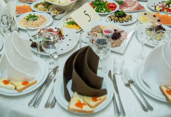 Table in restaurant with food on plates and snacks — Stock Photo, Image