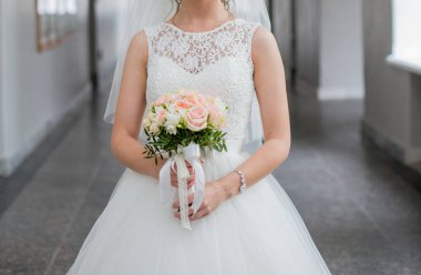 Gelin elinde bir buket düğün çiçeği tutuyor.