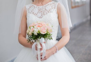 Gelin elinde bir buket düğün çiçeği tutuyor.