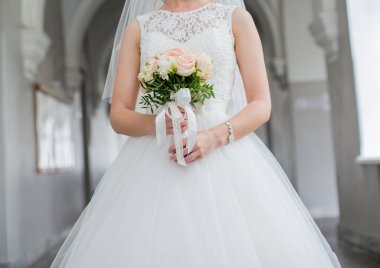 Gelin elinde bir buket düğün çiçeği tutuyor.