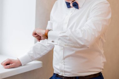 Beyaz gömlekli bir adam saatine bakıyor.