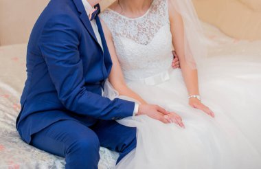 Gelin ve damadın yatakta oturuyor ve elele