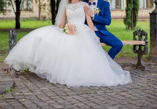 Braut und Bräutigam sitzen zusammen auf der Bank — Stockfoto