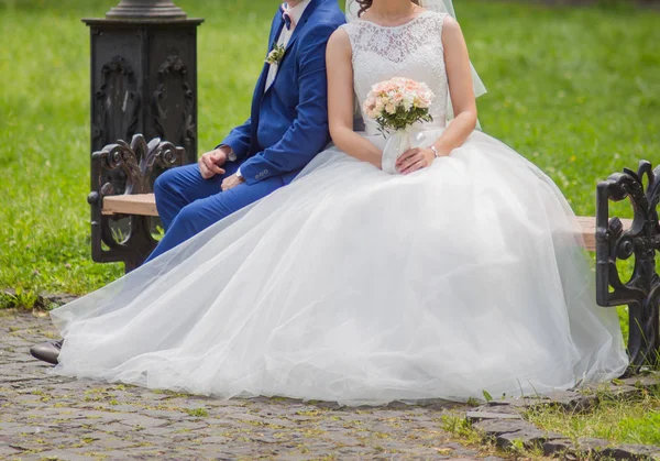 Les mariés sont assis sur un banc dans le parc — Photo