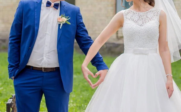 A noiva e o noivo dão as mãos na forma de um coração — Fotografia de Stock