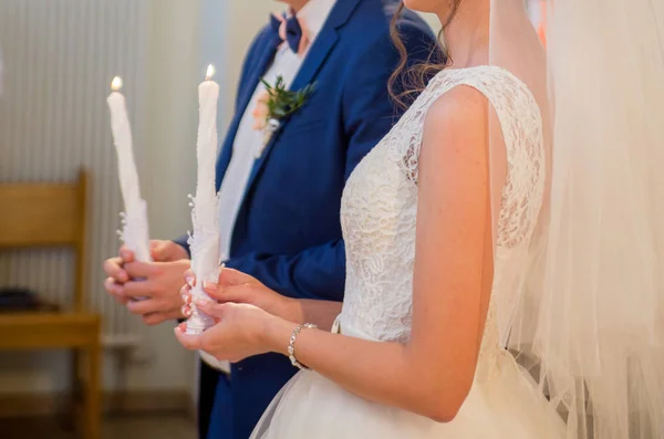 A noiva e o noivo segurando velas na igreja — Fotografia de Stock