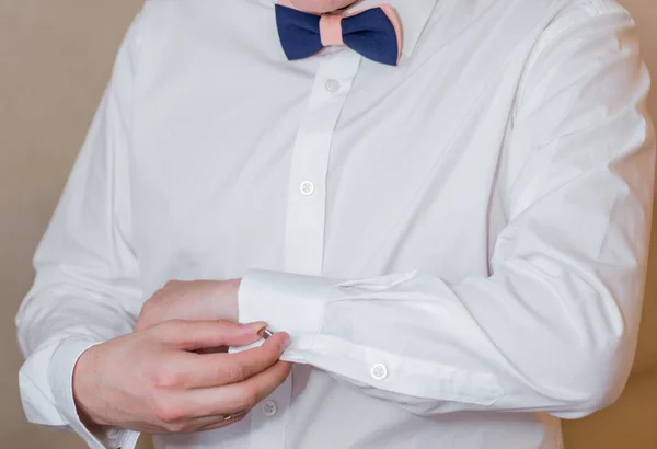 The groom fastens the button on the sleeve of the shirt — Stock Photo, Image