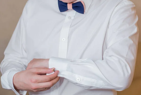 Жених закрепляет пуговицу на рукаве рубашки — стоковое фото
