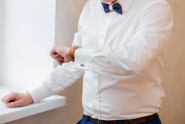 A man in a white shirt looks at his watch — Stock Photo, Image