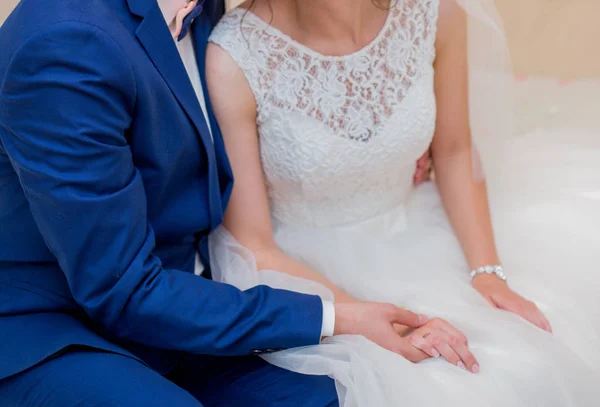 A noiva e o noivo estão sentados na cama e de mãos dadas — Fotografia de Stock