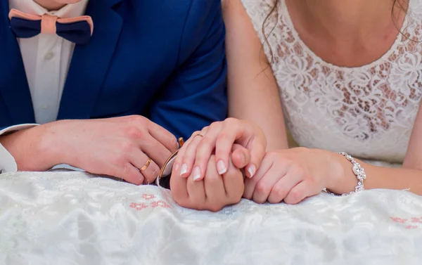 A menyasszony és a vőlegény az ágyon, és kezet tart — Stock Fotó