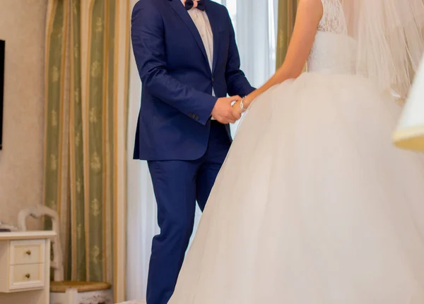 La mariée tient les mains du marié dans la chambre. — Photo