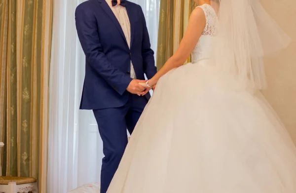 Невеста держит жениха за руки в комнате — стоковое фото