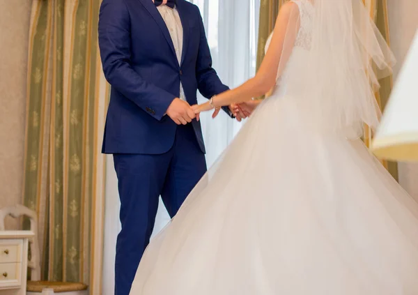 A noiva está segurando as mãos do noivo no quarto — Fotografia de Stock