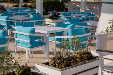 Mavi masa ve sandalyeler güneş ışığı altında açık havada kafe