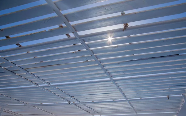 view of sky with shining sun through boat ceiling grid