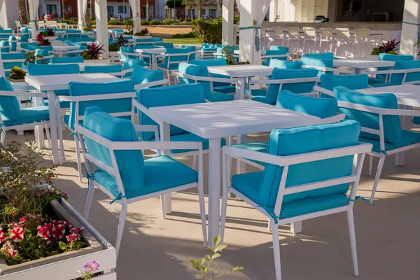 outdoors cafe with blue tables and chairs in sunlight
