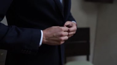 Adam ceketinin düğmesini bağlıyor.