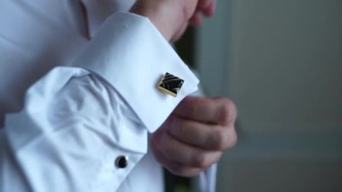 Adam gömlek koluna kol düğmesi takıyor.