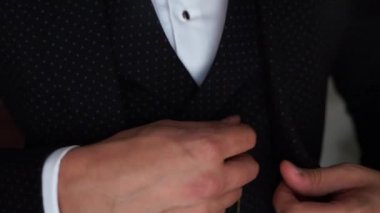 Adam düğmesini ceketine takıyor.